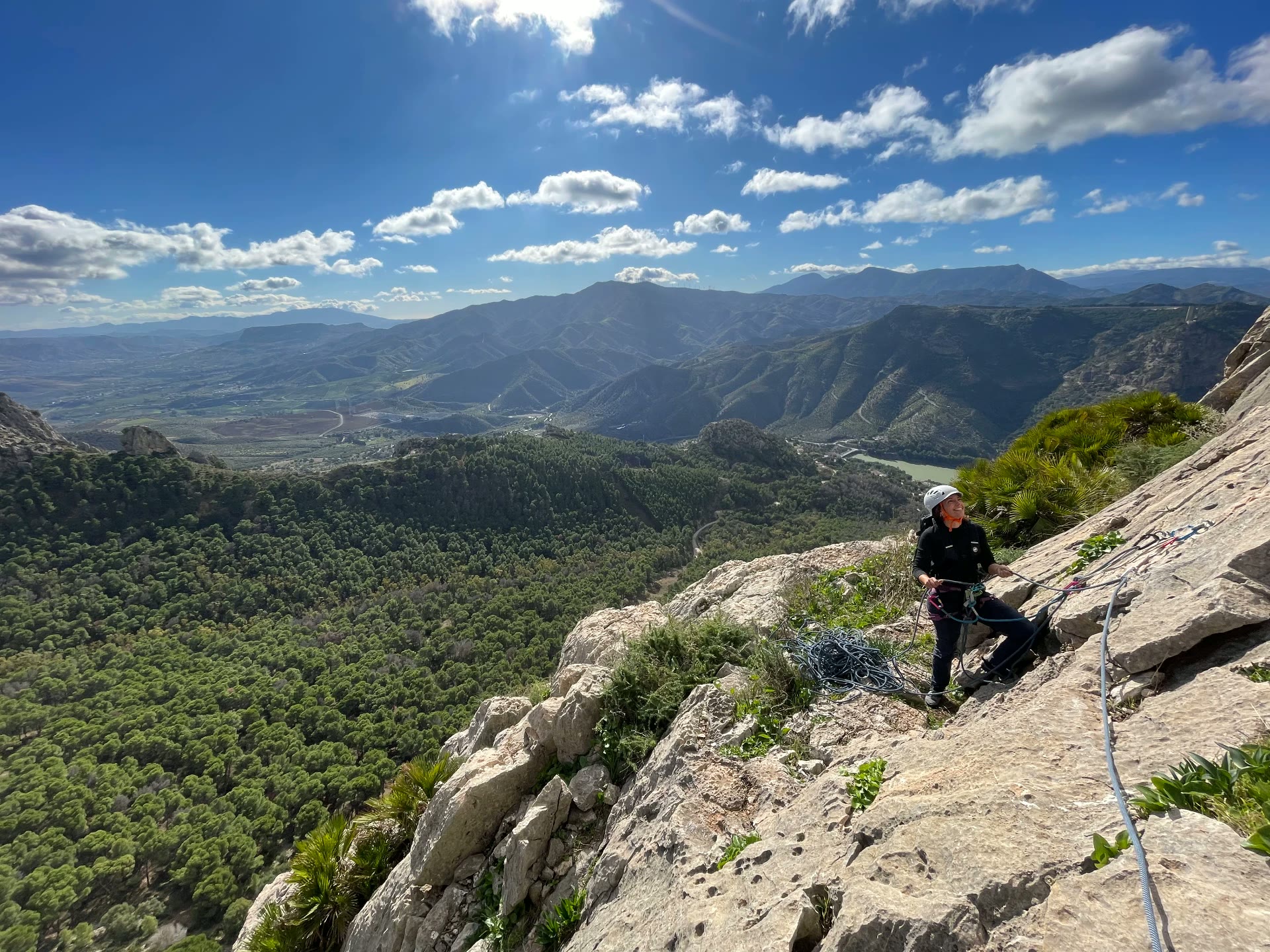 Learning to belay on a cliff ledge above the valley